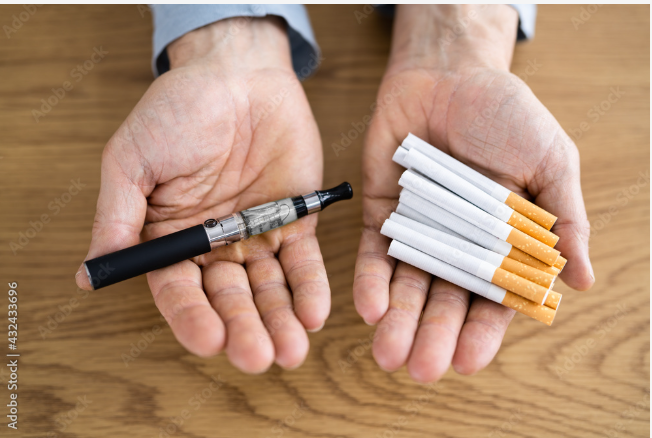 two hands holding an e-cigarette and traditional cigarettes