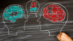 Two heads on chalkboard. One head with brain made up of blue puzzle pieces, the other head with a brain made up of red puzzle pieces. A speech bubble between the two heads demonstrating they are talking. Image in speech bubble shows a red and blue puzzle piece connecting.