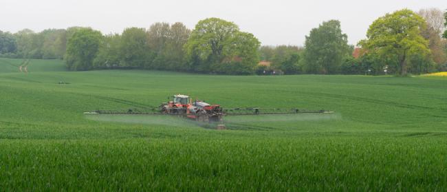 A tractor spreading pesticides A tractor spreading pesticides